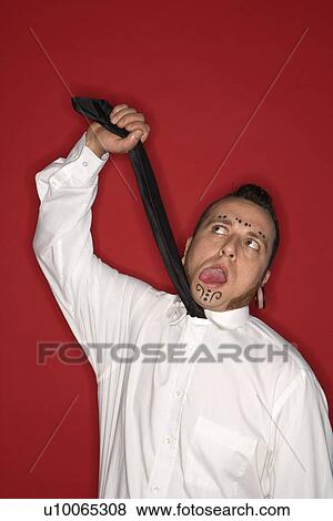 Caucasian mid-adult man with tattoos and piercings holding up necktie making facial expression. View Large Photo Image Stock Photo - Caucasian mid-adult man with tattoos and piercings holding up necktie making facial expression.. Fotosearch