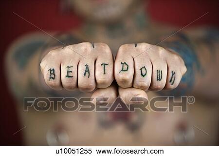 Stock Photography - Caucasian mid-adult man with tattoos and piercings holding out fists reading beat down.. Fotosearch
