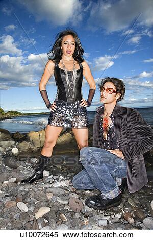 Stock Photography - Caucasian young male adult and African American female on rocky beach.. Fotosearch
