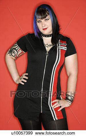 Stock Photo - Portrait of Caucasian woman with blue hair and tattoos wearing racing dress against orange background.. Fotosearch