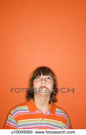 Head and shoulder portrait of Caucasian boy looking up standing against orange background. View Large Photo Image Stock Photography - Head and shoulder portrait of Caucasian boy looking up standing against orange background.. Fotosearch