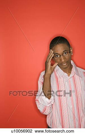 Portrait of African-American teen boy with glasses and hand on forehead against red background. View Large Photo Image Stock Image - Portrait of African-American teen boy with glasses and hand on forehead against red background.. Fotosearch