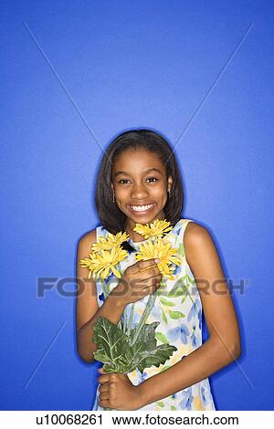Portrait of African-American teen girl holding a bouquet of daisies and smiling in front of blue background. View Large Photo Image Stock Image - Portrait of African-American teen girl holding a bouquet of daisies and smiling in front of blue background.. Fotosearch