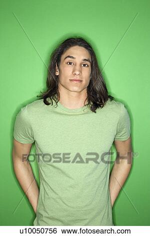 Stock Photograph - Portrait of Asian-American teen boy standing against green background.. Fotosearch