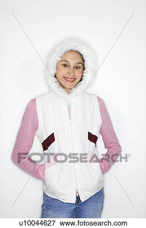 Stock Photo - Portrait of Asian-American teen girl with hands in coat pockets and furry hood on head smiling against white background.. Fotosearch