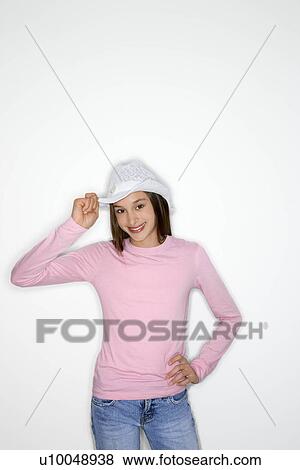 Stock Photo - Portrait of Asian-American teen girl tipping cowboy hat and hand on hip standing against white background.. Fotosearch