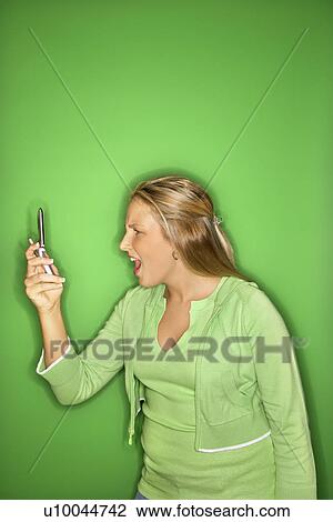 Portrait of blond Caucasian teen girl looking at cellphone with shock and disbelief against green background. View Large Photo Image Stock Image - Portrait of blond Caucasian teen girl looking at cellphone with shock and disbelief against green background.. Fotosearch