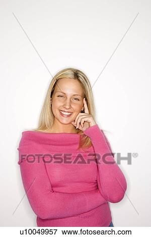 Stock Photo - Portrait of blond Caucasian teen girl standing against white background smiling wearing pink sweater.. Fotosearch