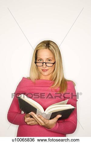Stock Photograph - Portrait of blond Caucasian teen girl wearing eyeglasses and holding a book looking at viewer. . Fotosearch
