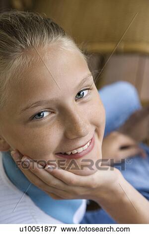 Stock Photo - Portrait of Caucasian pre-teen girl with chin in hand looking at viewer and smiling.. Fotosearch