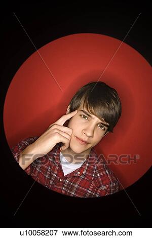 Stock Photo - Portrait of Caucasian teen boy pointing to his head.. Fotosearch