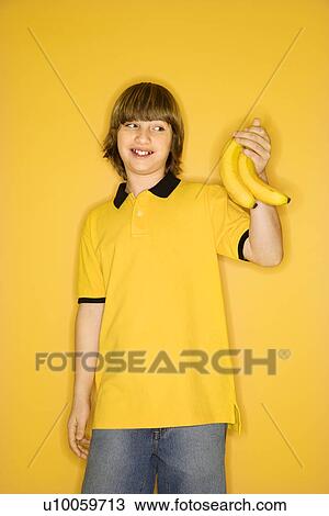 Portrait of smiling Caucasian boy holding bunch of bananas standing against yellow background. View Large Photo Image Stock Image - Portrait of smiling Caucasian boy holding bunch of bananas standing against yellow background.. Fotosearch
