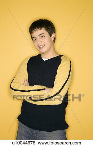 Portrait of smiling Caucasian teen boy with crossed arms standing against yellow background. View Large Photo Image Stock Photograph - Portrait of smiling Caucasian teen boy with crossed arms standing against yellow background.. Fotosearch