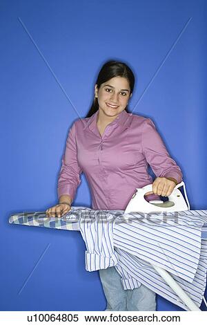 Portrait of smiling Caucasian teen girl ironing a shirt standing against blue background. View Large Photo Image Stock Photography - Portrait of smiling Caucasian teen girl ironing a shirt standing against blue background. . Fotosearch
