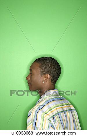 Stock Photo - Side view portrait of African-American teen boy against green background.. Fotosearch