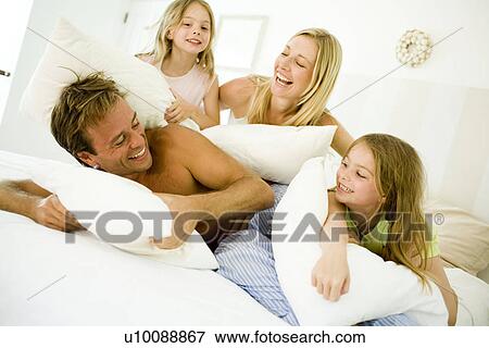 Stock Photo - Family at home having pillow fight. Fotosearch