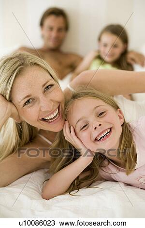 Stock Image - Family at home parents in bed. Fotosearch