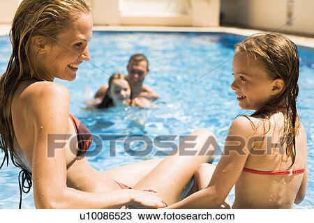 Stock Image - Family playing in pool. Fotosearch