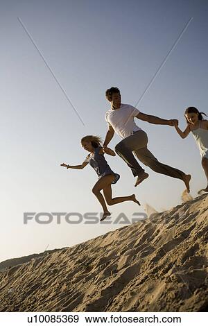 Family playing on beach, jumping off dune View Large Photo Image Stock Photo - Family playing on beach, jumping off dune. Fotosearch