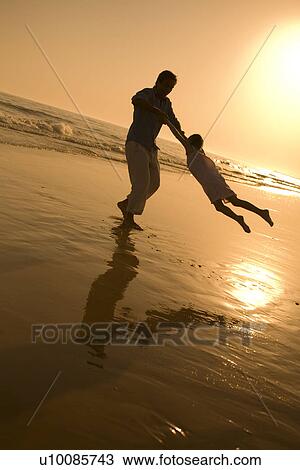 Stock Image - Family playing on beach. Fotosearch