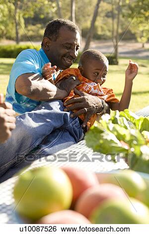 Stock Photograph - Grandfather and grandson at picnic in park. Fotosearch