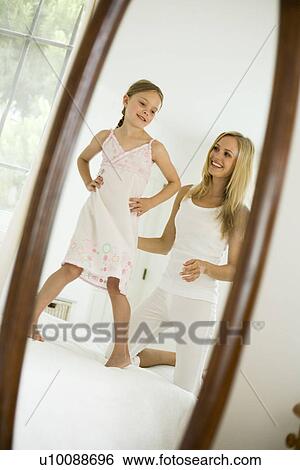 Stock Photograph - Mother and daughter looking in mirror. Fotosearch