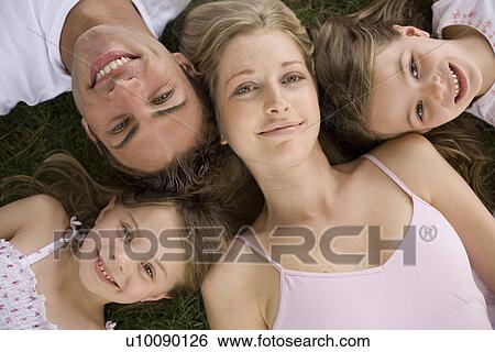Stock Photograph - Family lying on grass. Fotosearch