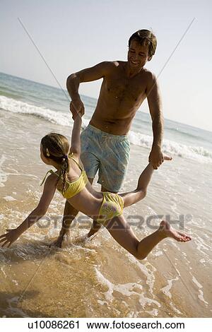 Stock Image - Family on beach playing together. Fotosearch