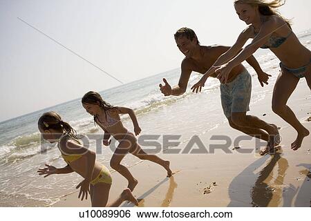 Stock Photograph - Family on beach playing together. Fotosearch