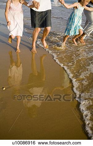 Stock Photograph - Family walking on beach. Fotosearch