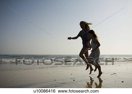 Stock Photograph - Mother and daughter on beach playing together. Fotosearch