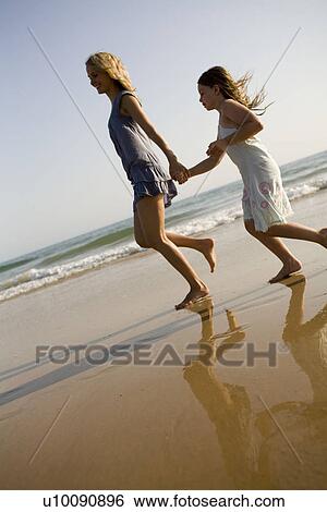 Stock Photograph - Mother and daughter playing together on beach. Fotosearch