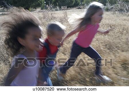Two girls and a boy running in field View Large Photo Image Stock Image - Two girls and a boy running in field. Fotosearch