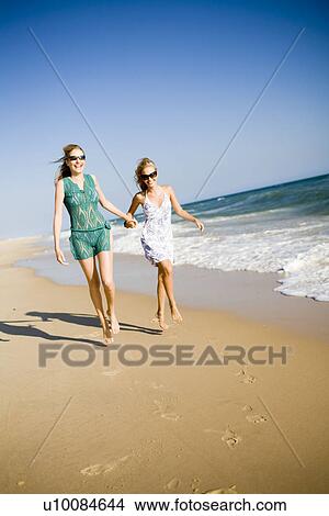 Picture - Two women walking on beach. Fotosearch