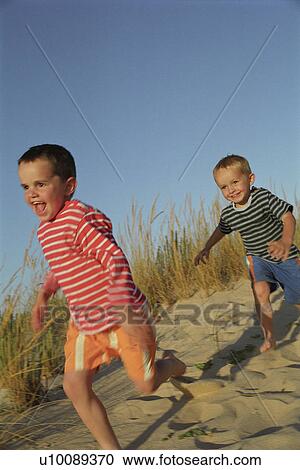 Stock Image - Children running in sand dunes. Fotosearch