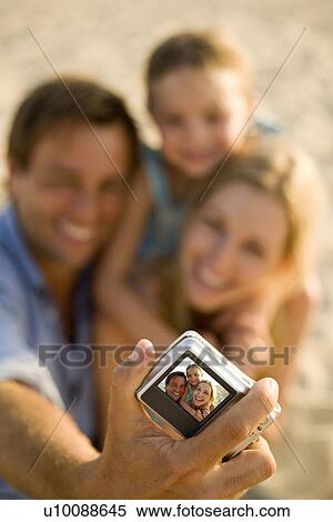 Stock Photography - Family on beach with camera. Fotosearch