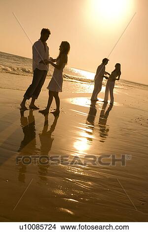 Picture - Two couples walking on beach . Fotosearch