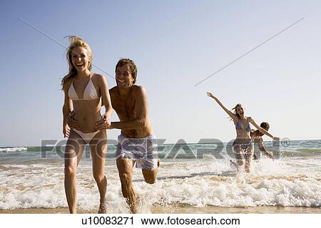 Stock Image - Two young couples on beach. Fotosearch