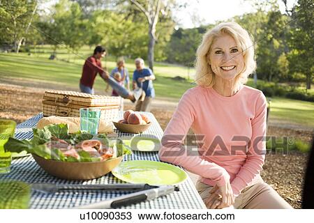 Stock Image - Grandparents and family in park with picnic. Fotosearch