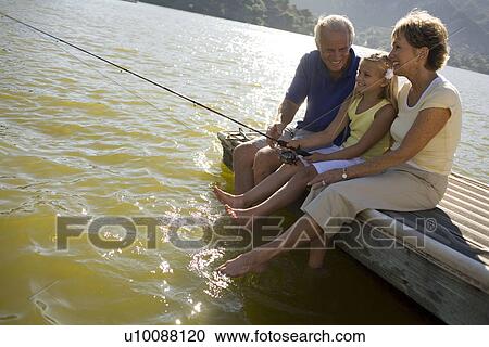Stock Image - Mature couple with grandchild by lake fishing. Fotosearch