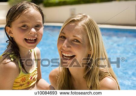 Stock Image - Mother and daughter playing in pool. Fotosearch