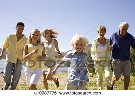 Standartinė fotografija - Three Generations of family running by lake. Fotosearch