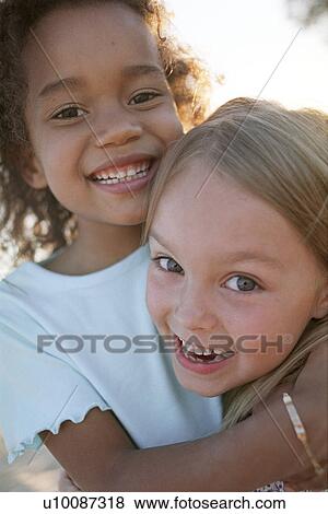 Two young girls hugging View Large Photo Image Stock Photo - Two young girls hugging. Fotosearch