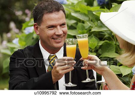 Close-up of a couple toasting glasses of juice View Large Photo Image Stock Image - Close-up of a couple toasting glasses of juice. Fotosearch