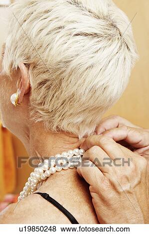Close-up of a mature man putting a pearl necklace around a mature woman's neck View Large Photo Image Stock Photo - Close-up of a mature man putting a pearl necklace around a mature woman's neck. Fotosearch