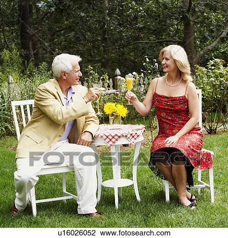 Mature couple looking at each other holding glasses of juice View Large Photo Image Stock Image - Mature couple looking at each other holding glasses of juice. Fotosearch