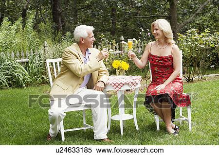 Stock Photography - Mature couple looking at each other holding a glass of juice. Fotosearch