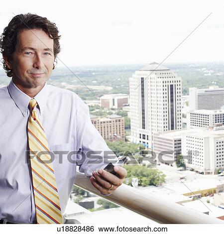 Portrait of a businessman holding a mobile phone View Large Photo Image Stock Photograph - Portrait of a businessman holding a mobile phone. Fotosearch