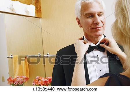 Stock Image - Rear view of a mature woman adjusting bow tie of a mature man. Fotosearch