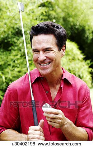 Close-up of a mature man holding a golf club and a golf ball View Large Photo Image Stock Photo - Close-up of a mature man holding a golf club and a golf ball. Fotosearch